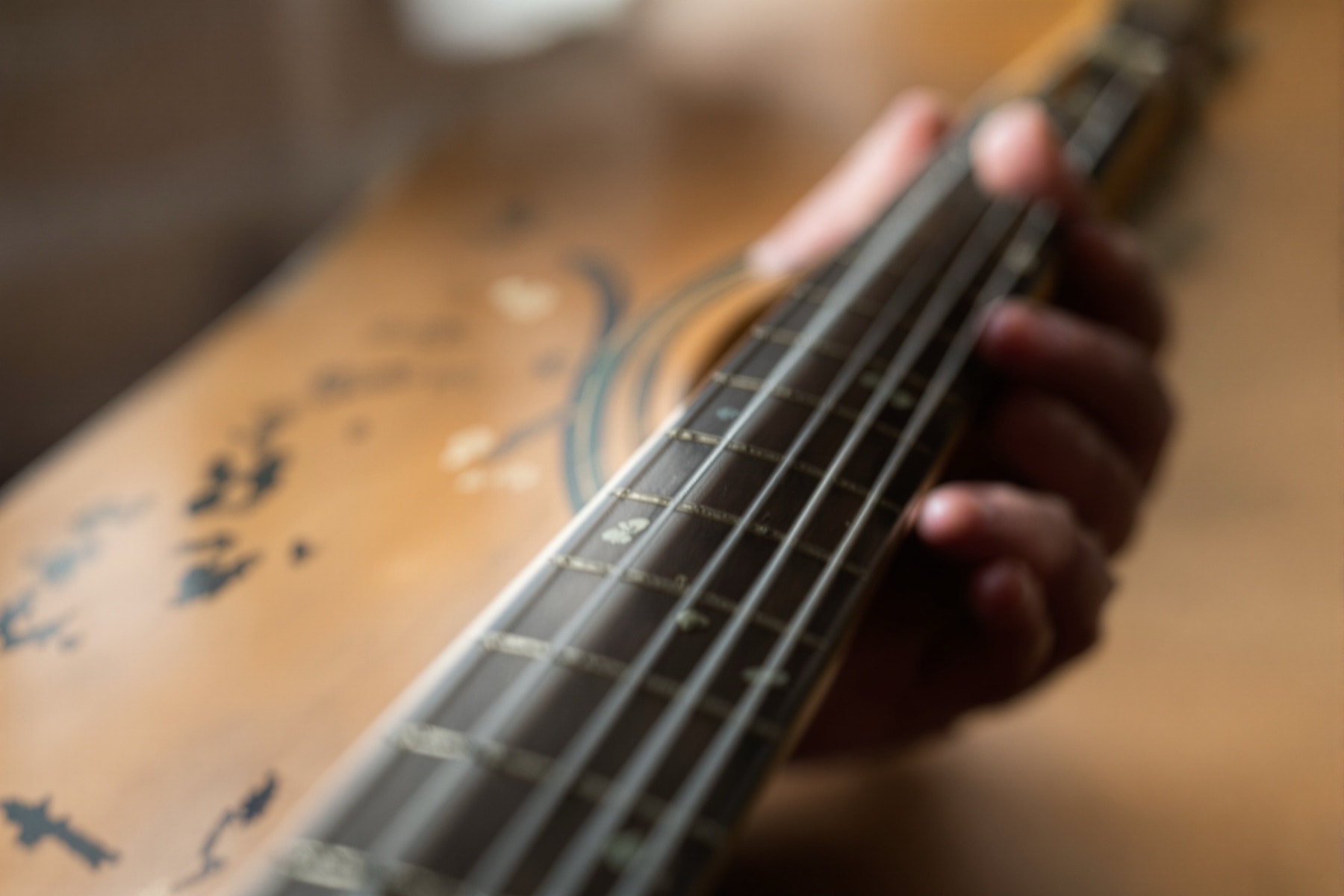 Close-up of a right hand fingerpicking a worn acoustic guitar